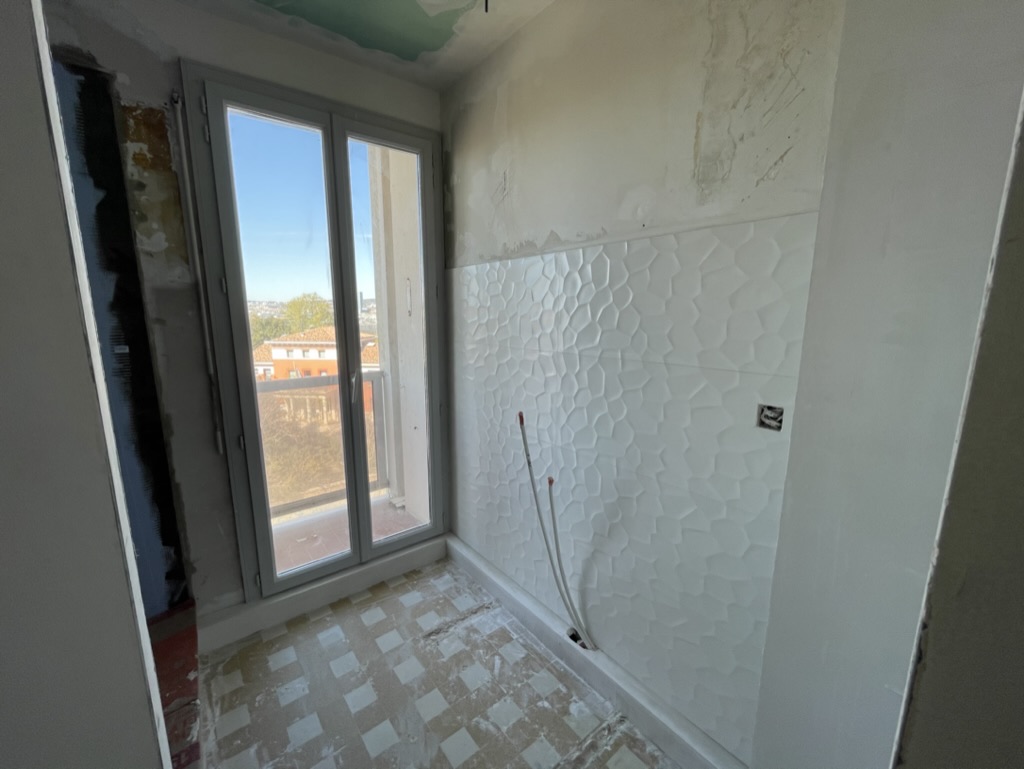 Salle en rénovation avec murs et sols en cours de reprise.